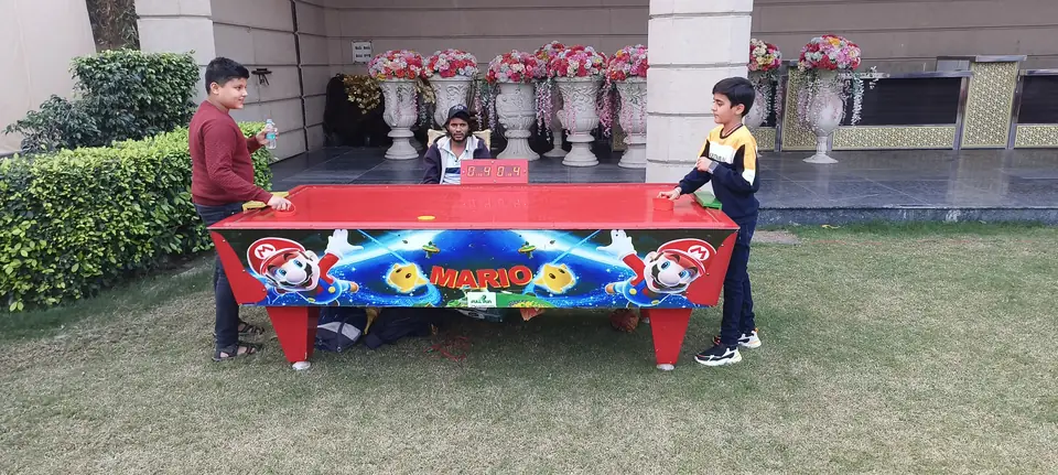 Kids enjoying an air hockey table during a Goa celebration