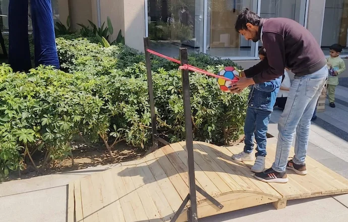 Parent helping a child play the Angry Bird slingshot game at a Gurgaon event